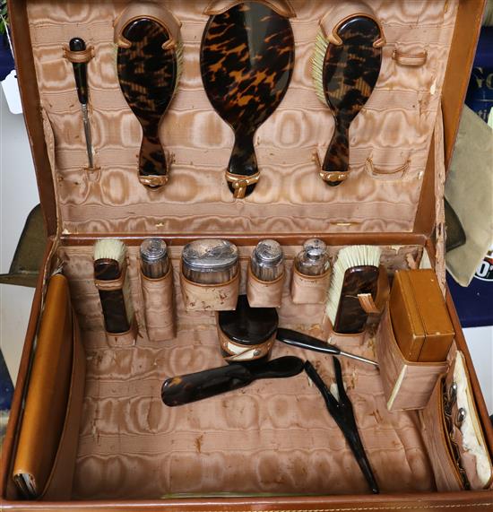 A leather travelling toilet case containing four late Victorian silver mounted jars and thirteen tortoiseshell mounted items.